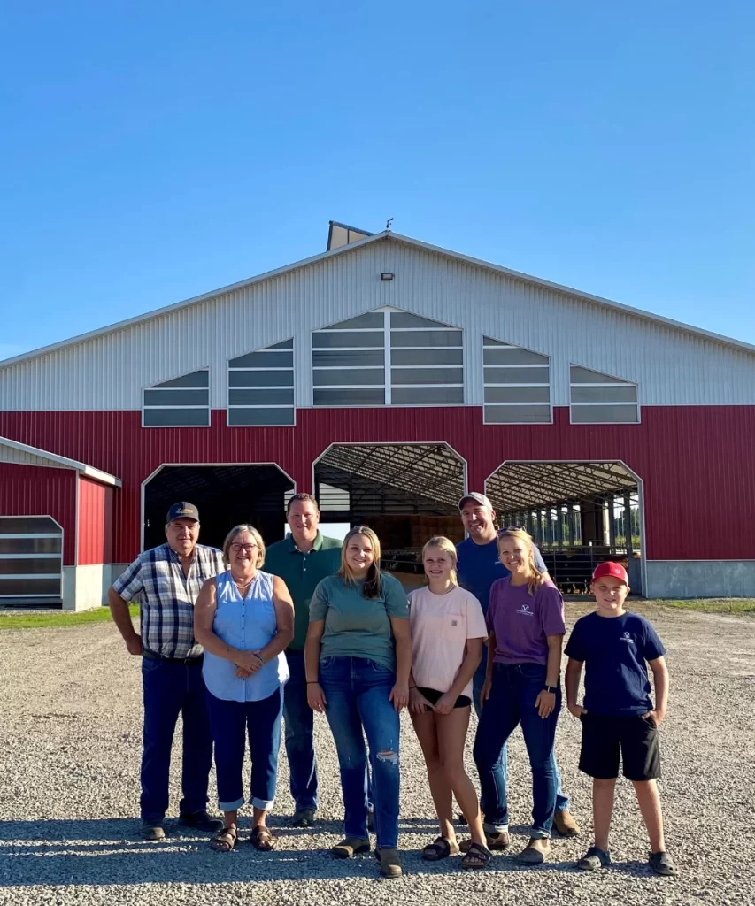Aaron Meidema standing alongside a family of policyholders in front of a large barn, representing the personalized farm insurance services offered by CTM.