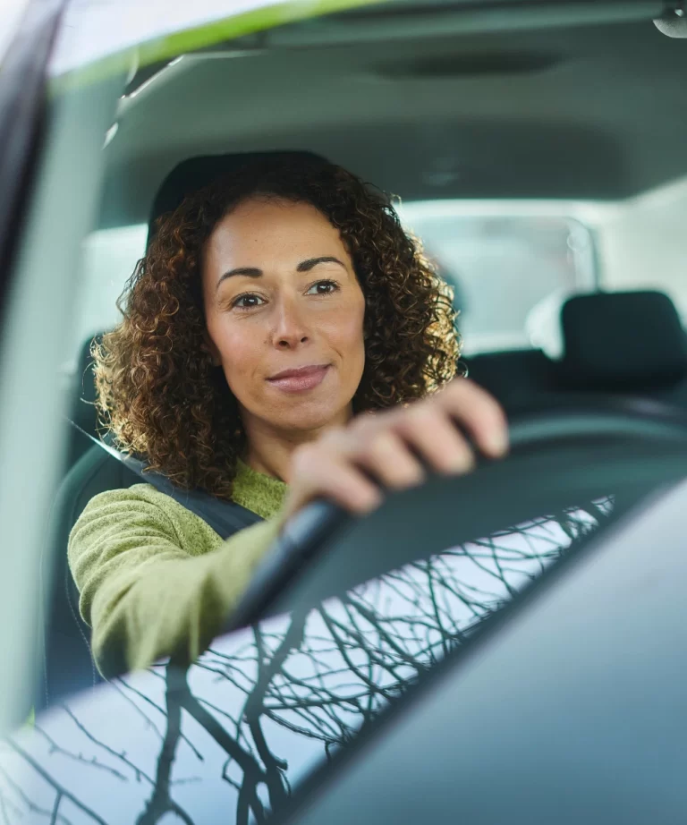 Woman driving a car, enjoying a smooth ride with peace of mind, knowing her vehicle is covered by CTM Insurance for comprehensive auto protection.